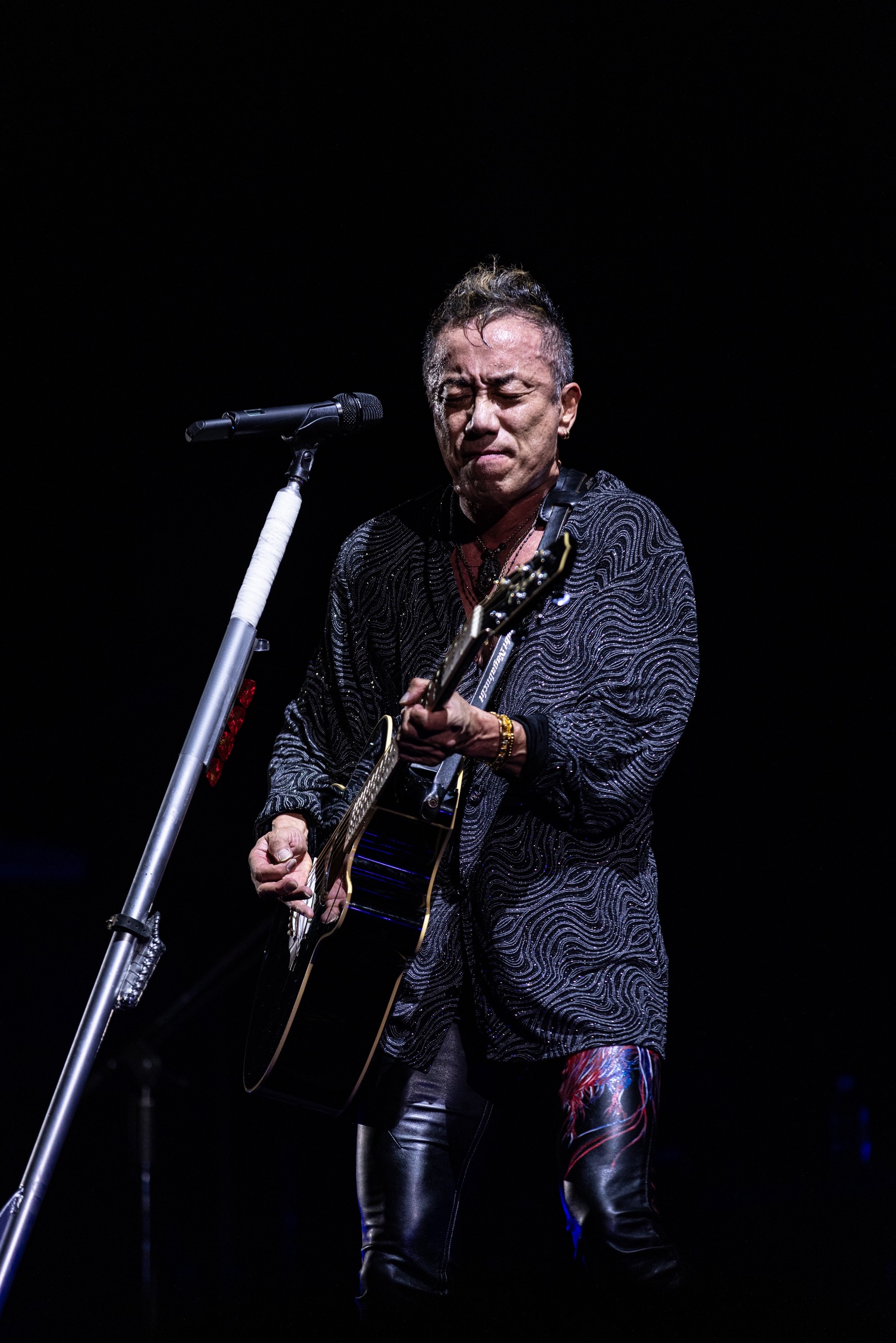 マイク前でギターを弾く男性