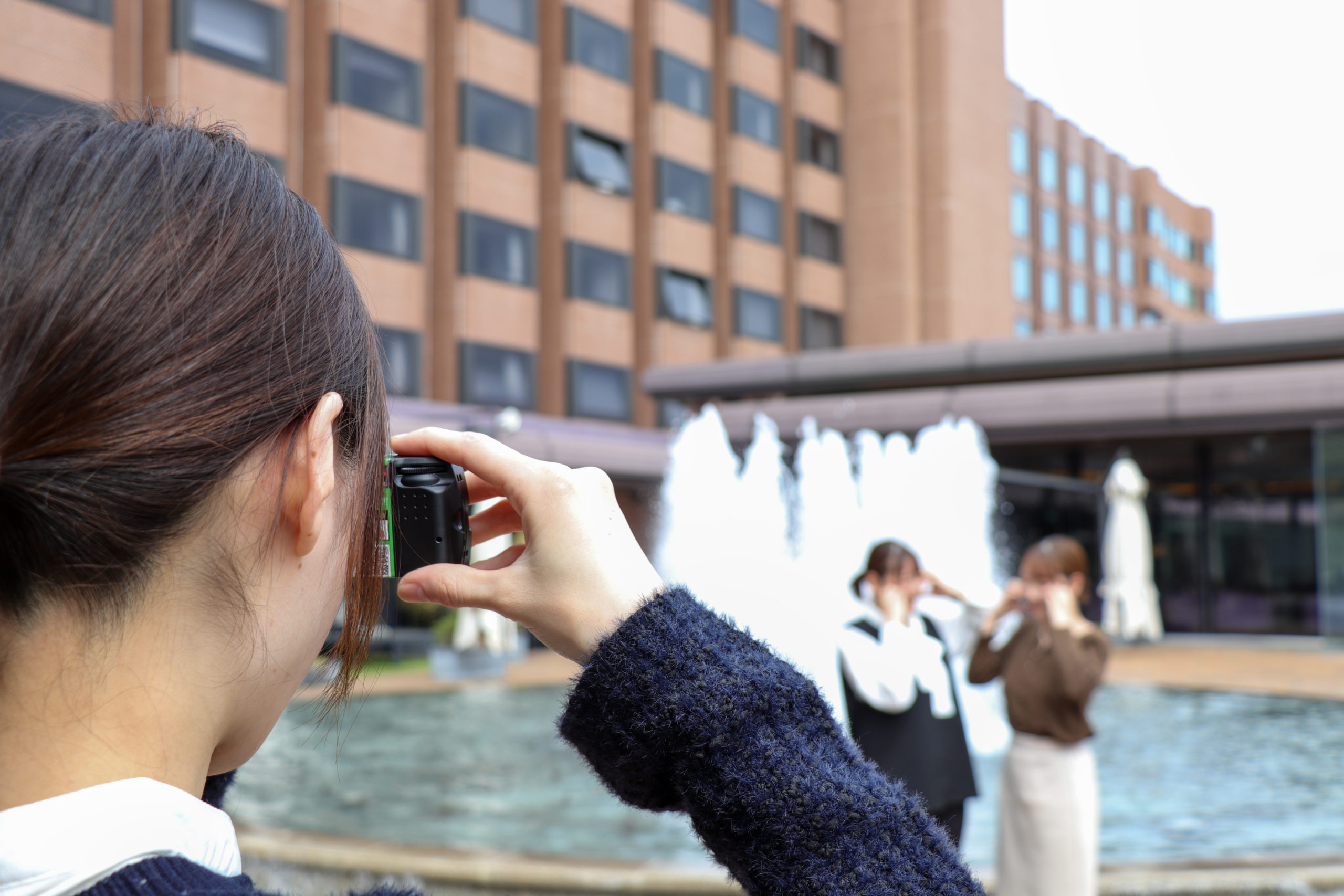 写真を撮る女性と噴水
