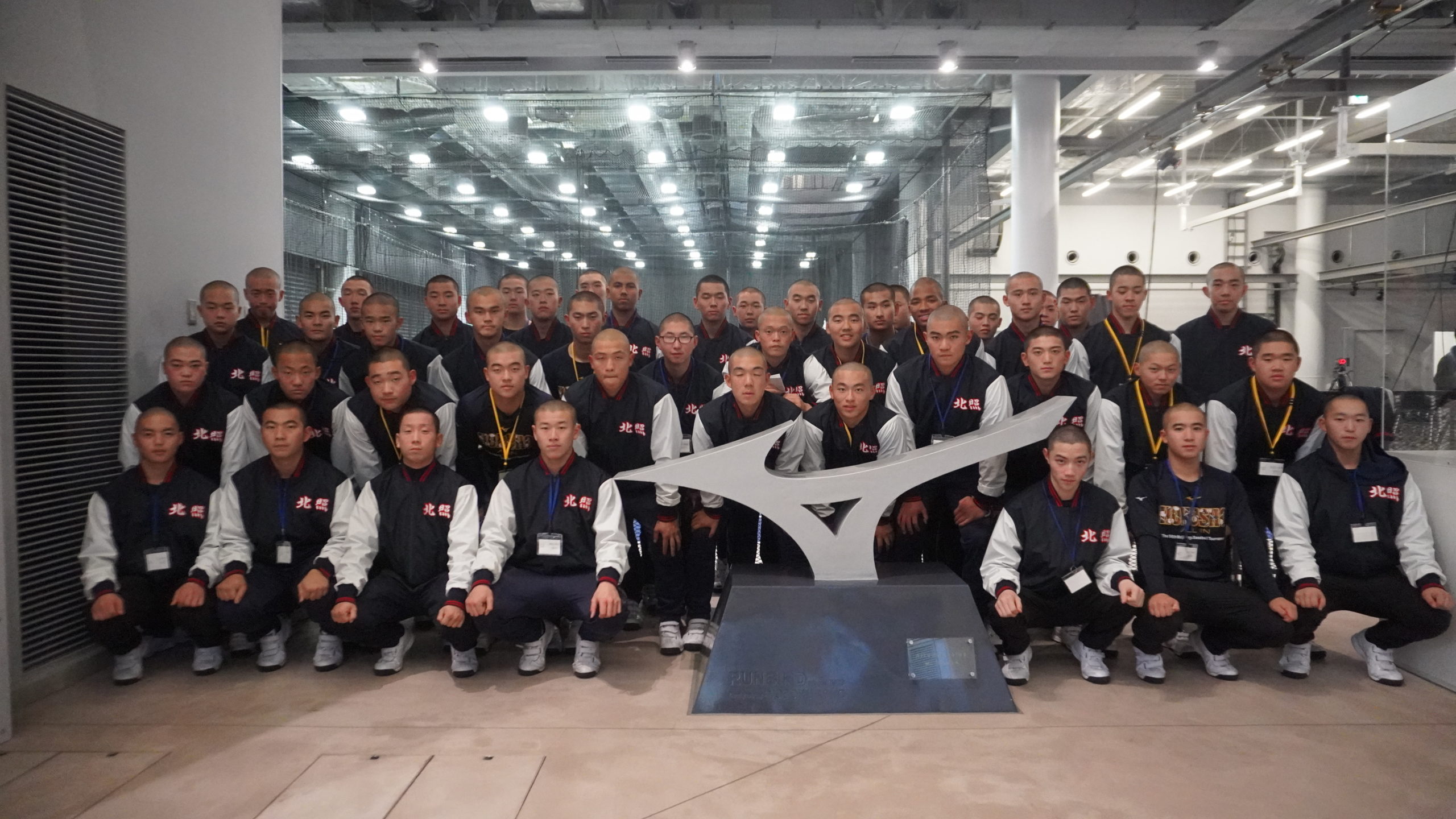 大勢の学生が記念碑の前に立つ