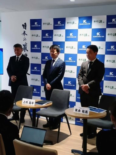 企業記者会見で並ぶ三人の男性