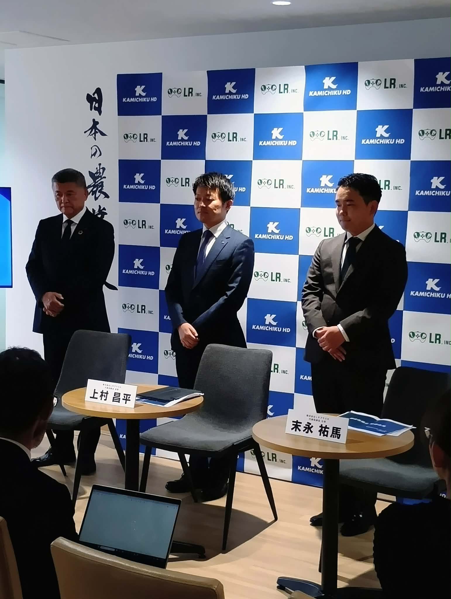 企業記者会見で並ぶ三人の男性