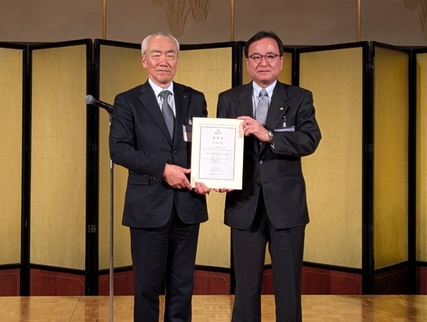 表彰状を掲げるスーツ姿の二人の男性